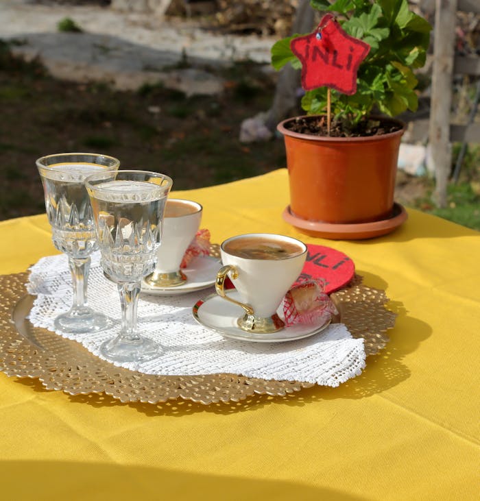 who-we-are Charming outdoor setup with coffee cups and glasses on a yellow tablecloth, perfect for al fresco dining.
